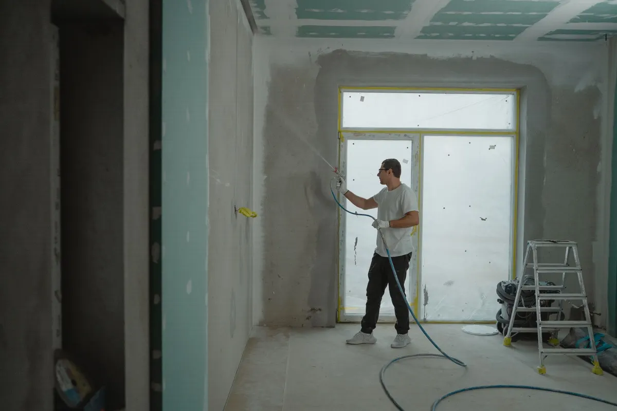 Handwerker beschichtet eine Wandfläche in einer Wohnung im Rohausbau